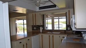 A kitchen with white cabinets, a dishwasher, a stove, and a ceiling fan. - "Water's Edge" Beautiful Waterfront Home In Edgewater, Florida (Edgewater)