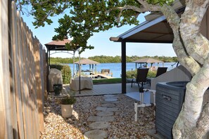 Un patio extérieur couvert avec vue sur un lac, des marches en pierre, du mobilier d’extérieur et un chauffe-eau.