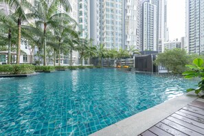 A swimming pool surrounded by tall residential buildings and palm trees.