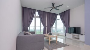 A modern living room with a grey sofa, a wooden coffee table, a flat-screen TV, and a ceiling fan. - OYO Home 89736 Unbelievable 2br 1medini (Iskandar Puteri)