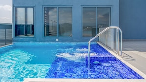 Un bâtiment moderne doté de grandes fenêtres et d’une piscine aux carreaux de mosaïque bleus.