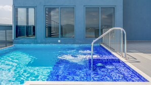 Ein modernes Gebäude mit großen Fenstern und einem Swimmingpool mit blauen Mosaikfliesen.