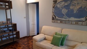 Una sala de estar con un sofá color beige, una mesa de centro de madera y un mapa mundial en la pared.