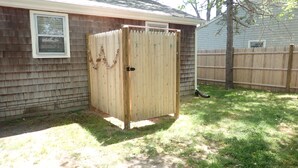 A wooden shed with a door, located in a backyard with a wooden fence and a tree. - ** Labor day on 3day min. Beach 0.7 Mi walk- Craigville & Covell. A/C, bikes. (Barnstable)