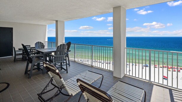 A balcony with a view of the ocean, a table with chairs, and a swing chair.
