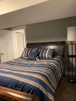 A bedroom with a bed, a nightstand, a lamp, and a door with numbers. - Mountain views, Hiking, skiing and park !  Coffee, hot chocolate and waffles! (Vineyard)