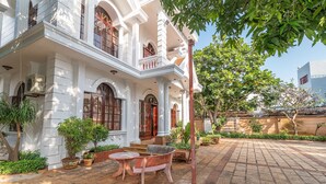 Un bâtiment blanc doté d’un balcon, de plantes en pot et d’un espace patio avec une table et des chaises.
