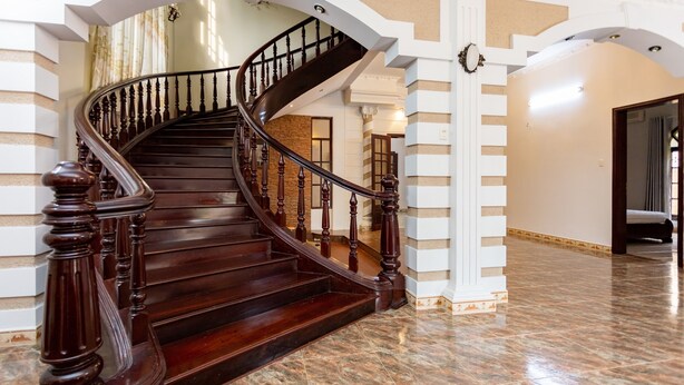 Un magnifique escalier en bois foncé, avec des marches et des balustrades, menant à l’étage supérieur.