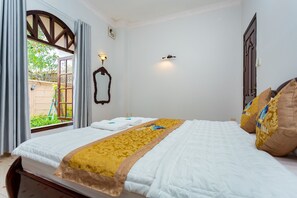 A neatly made bed with a white and gold bedspread, a wooden headboard, and two decorative pillows.