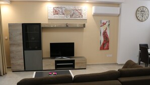 Una sala de estar moderna con una televisión de pantalla plana, una chimenea, una mesa de centro y un sofá.