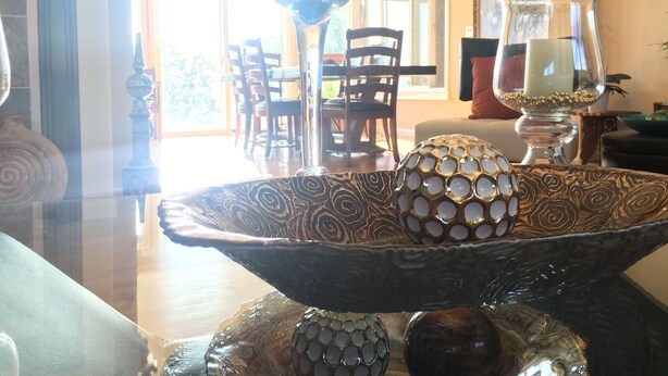 Un comedor con un cuenco decorativo grande sobre una mesa, rodeado de sillas.