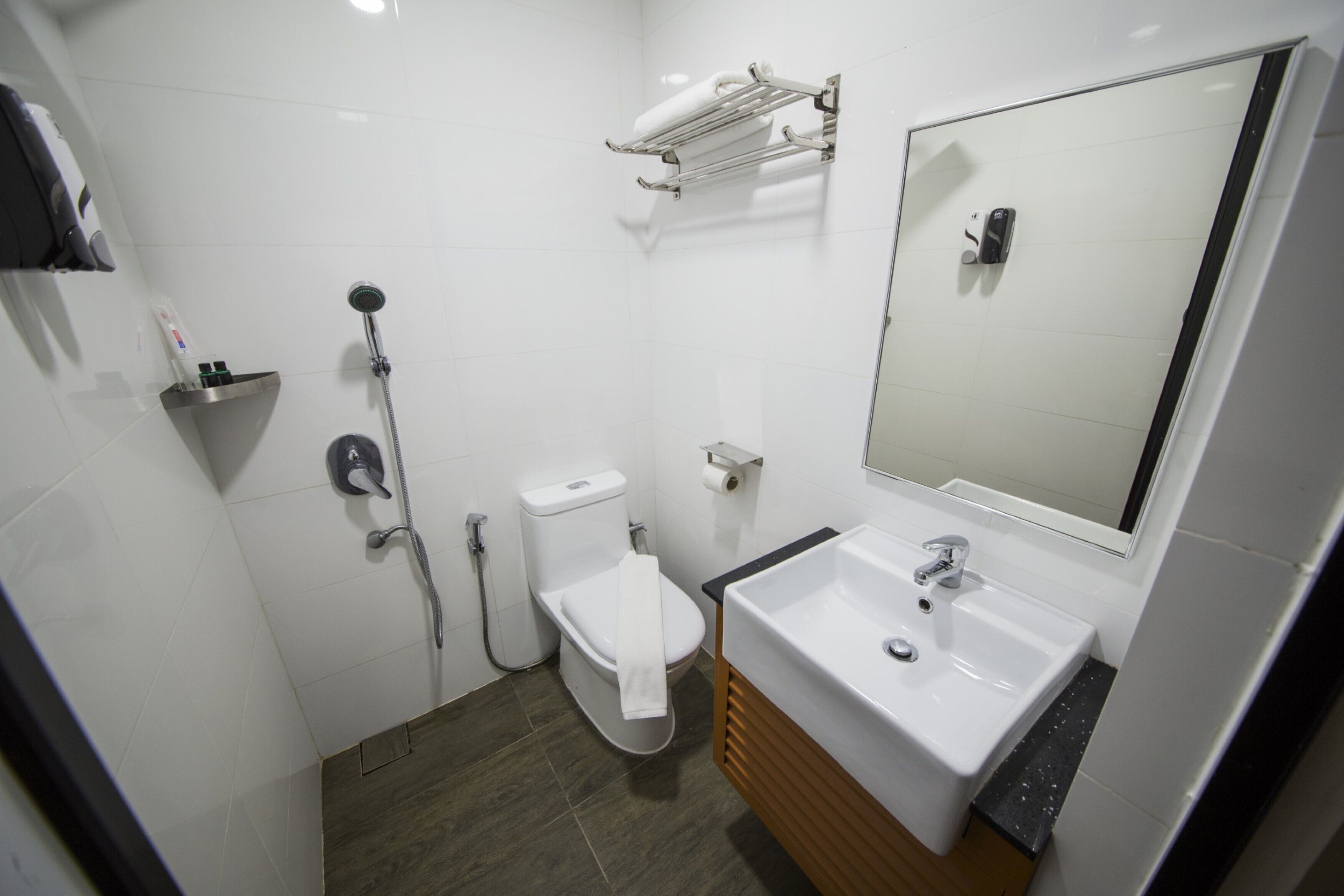 A modern bathroom with a white sink, mirror, and toilet.