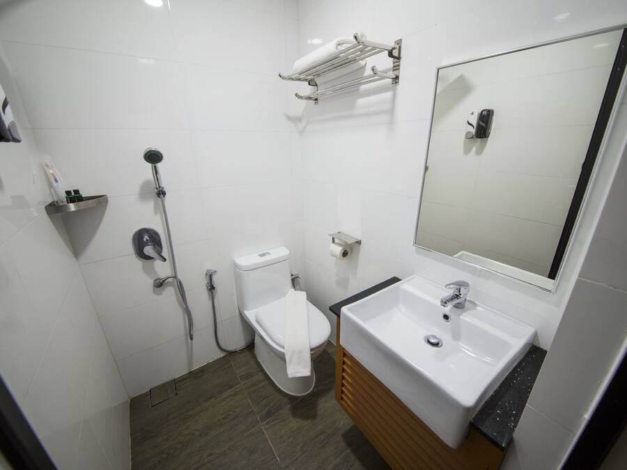 A modern bathroom with a white sink, mirror, and toilet.
