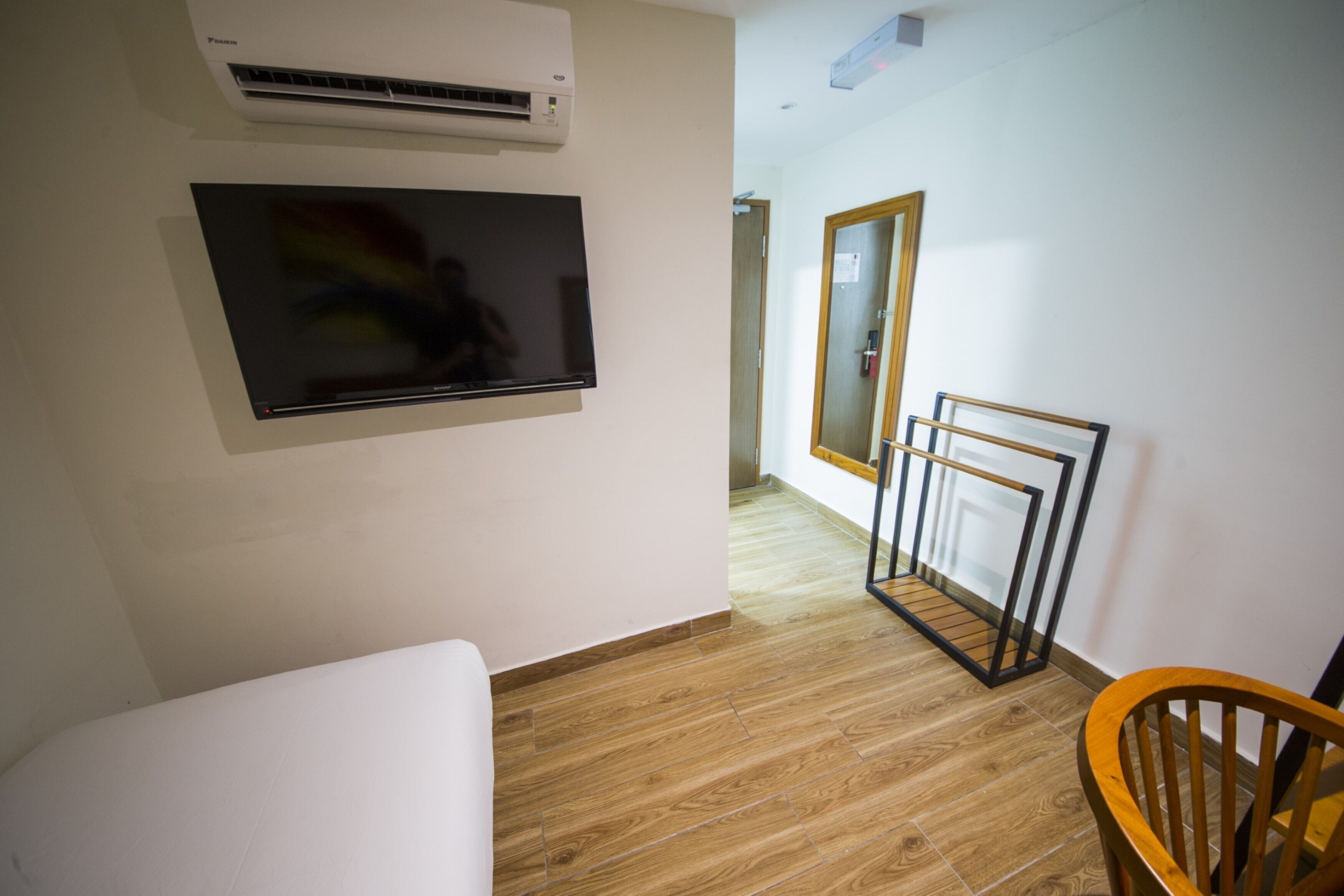 A room with a flat-screen TV mounted on the wall, a wooden floor, and a chair.