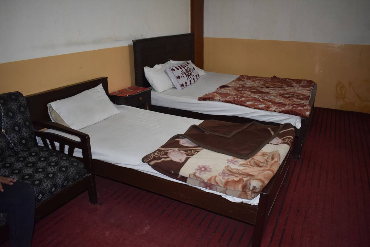 A room with two single beds, a wooden chair, and a small table.