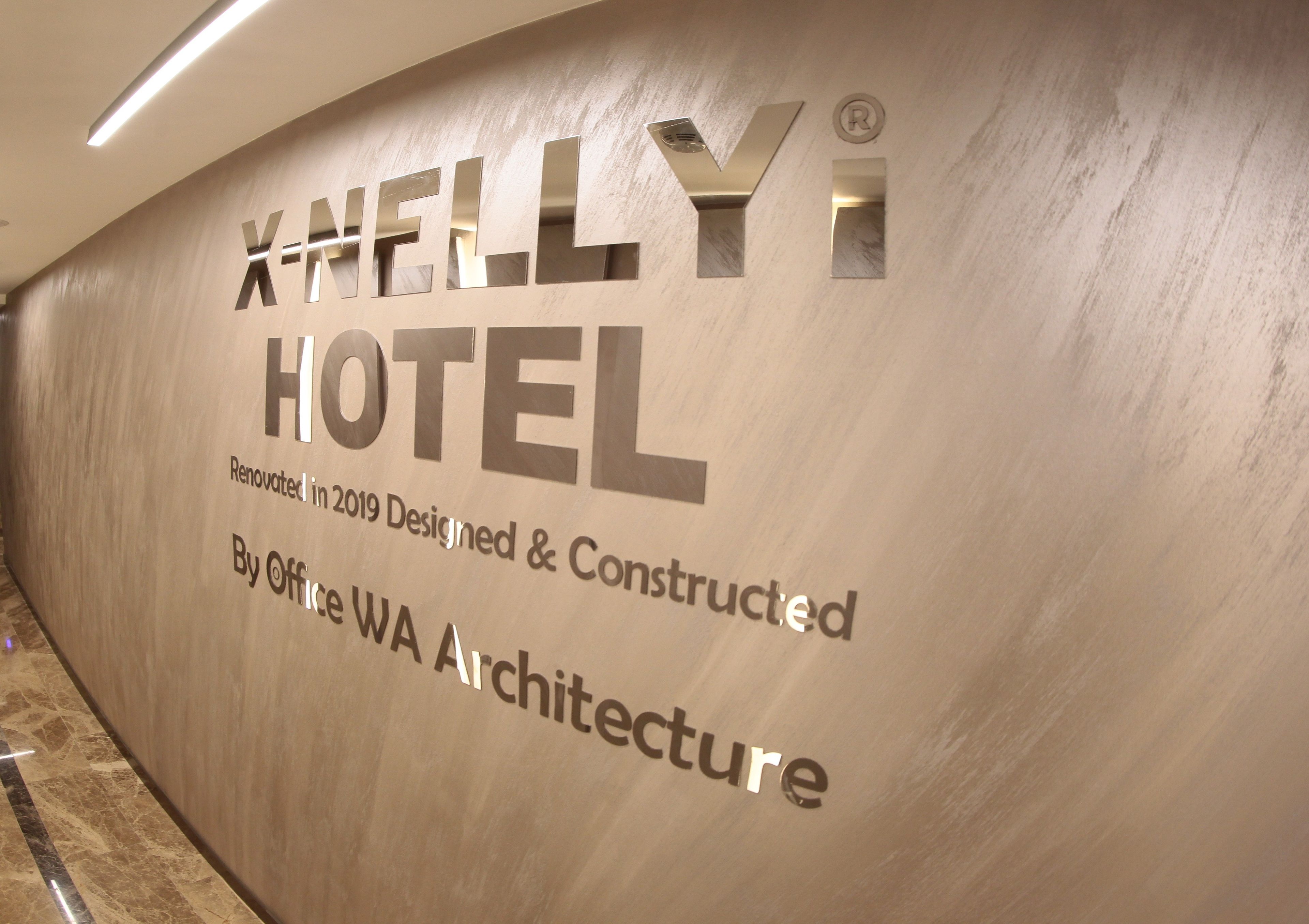 A wall with the text 'XHELLY HOTEL' and 'Renovated in 2019 Designed & Constructed By Office WA Architecture'.