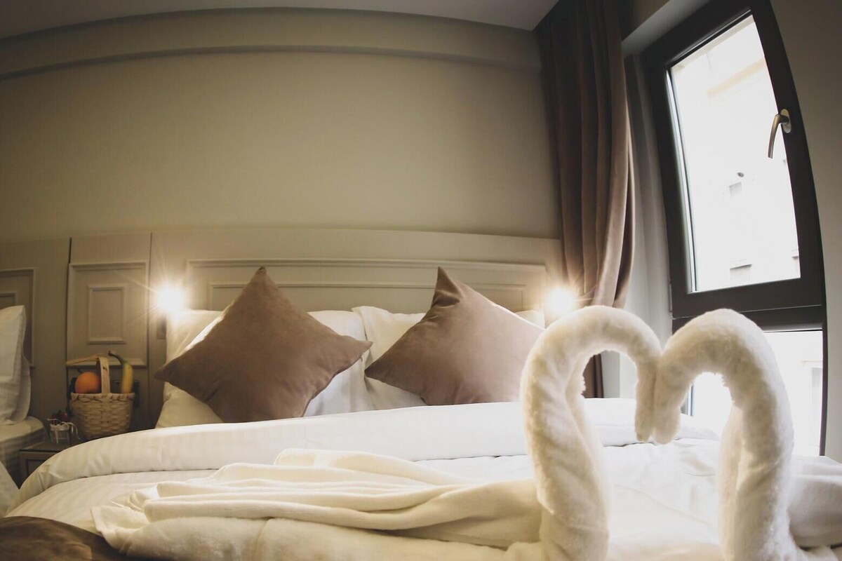 Une chambre d’hôtel avec un lit, des oreillers, une table de chevet et une fenêtre.