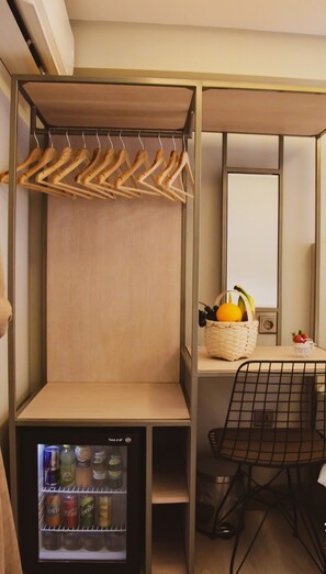 A compact room with a kitchenette area, a small refrigerator stocked with beverages, a wooden hanger rack, and a wicker basket with fruits. - X-Nellyi Boutique Hotel (Istanbul)