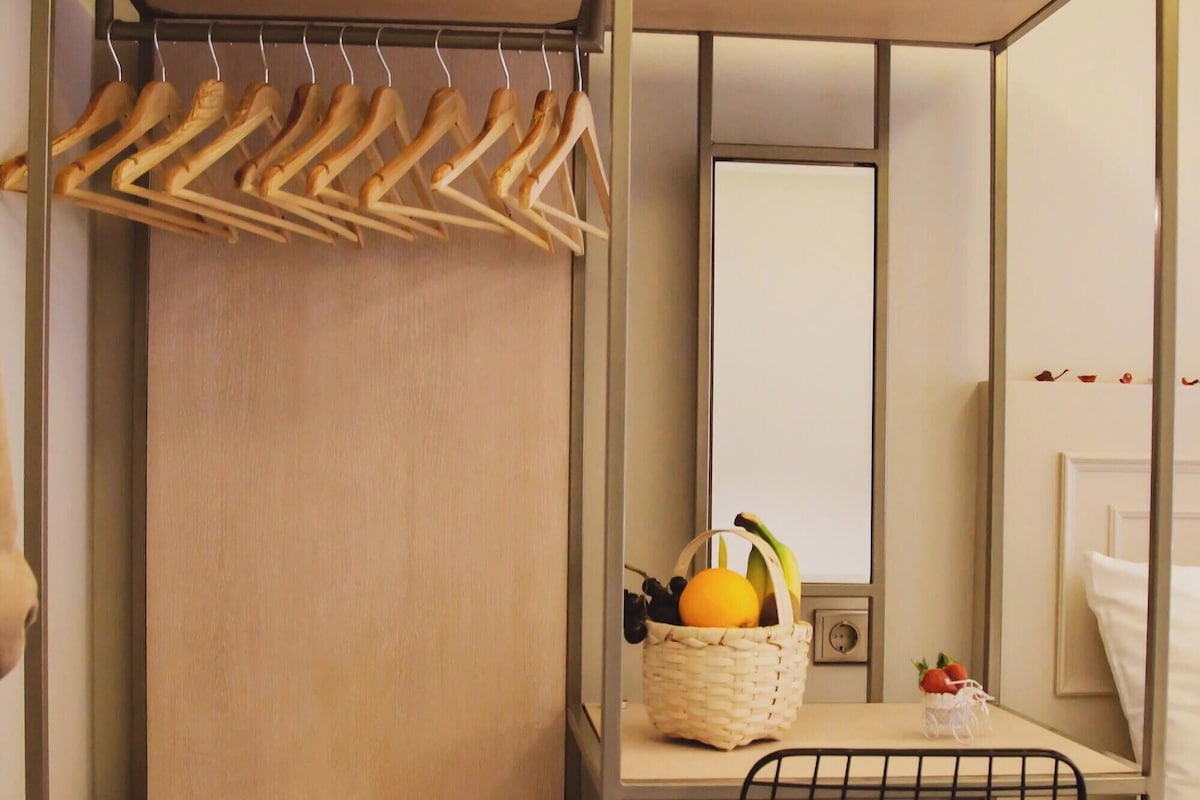Une chambre d’hôtel compacte comprenant un placard, une petite kitchenette, un coin repas et un lit.