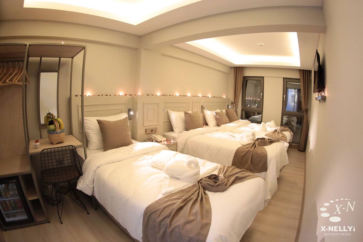 A hotel room with two beds, a minibar, a seating area, and a large mirror.