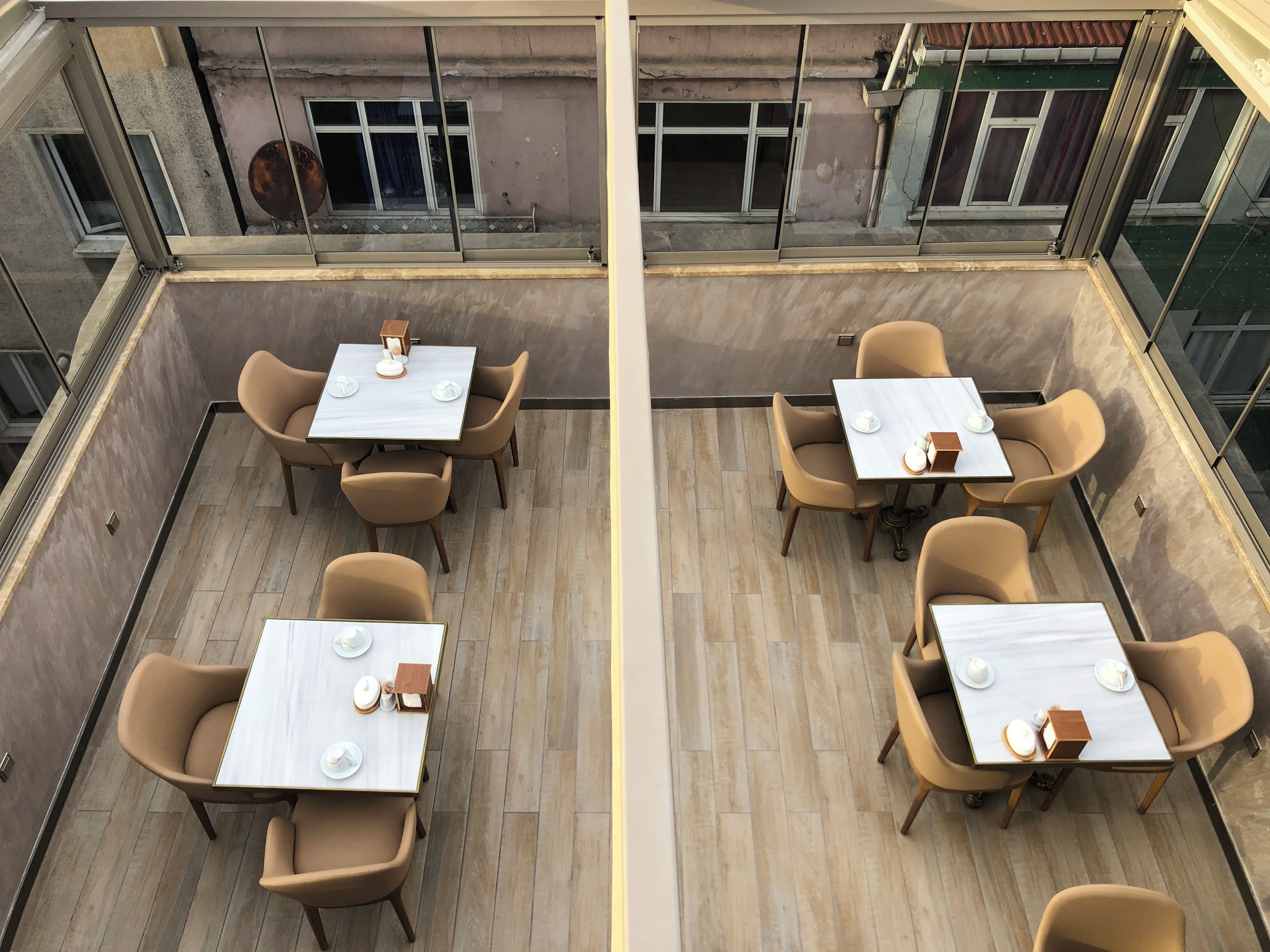 Une terrasse sur le toit, aménagée avec quatre tables et des chaises, chaque table étant dressée avec de la vaisselle blanche.
