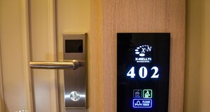 Porta de quarto de hotel com visor digital indicando o número 402, leitor de cartão-chave e um aviso de 'NÃO PERTURBAR'.