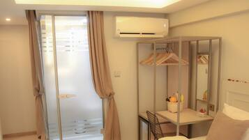 Une chambre d’hôtel comprenant un lit, une table de chevet, un miroir, une armoire et un appareil de climatisation.