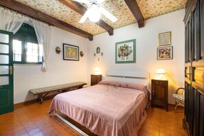 A bedroom with a bed, a bench, a nightstand, a chair, and a ceiling fan.