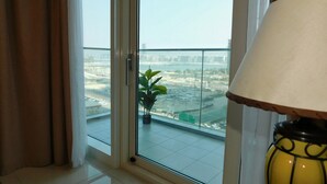 A room with a large window, a potted plant, and a lamp. - Luton Vacation Homes Damac Heights (Dubai)