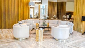 A modern hotel lobby with a large seating area, a marble floor, and a large mirror reflecting the interior. - Luton Vacation Homes Damac Heights (Dubai)