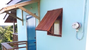Un edificio pequeño con puerta azul, rampa de madera y una ventana.