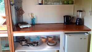 Una cocina compacta con cubierta de madera, un refrigerador pequeño y un estante con utensilios de cocina.