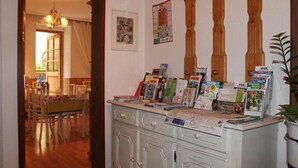 Une pièce comprenant un coin repas, un meuble en bois contenant des brochures et un panneau de signalisation vert indiquant la sortie.