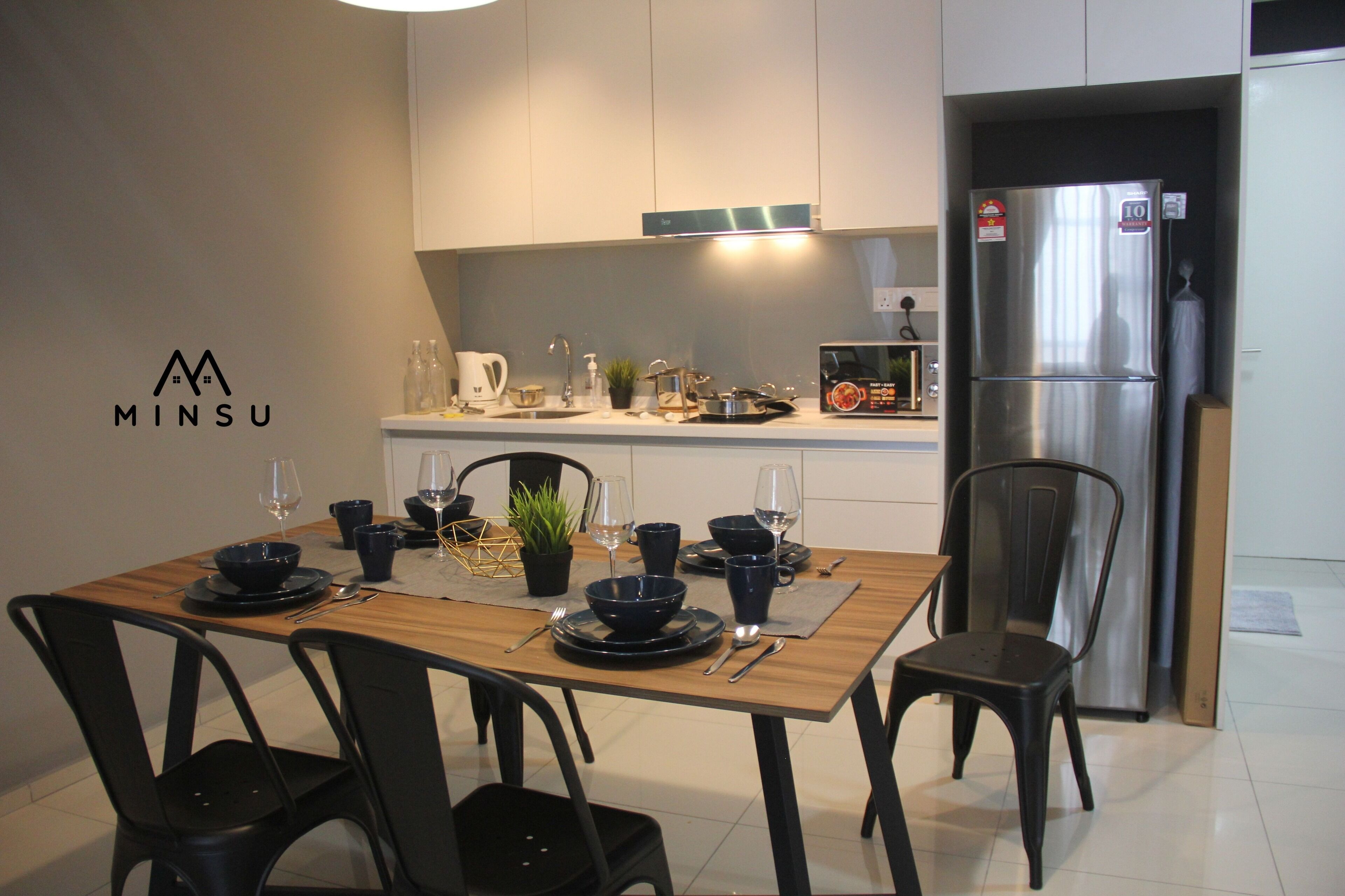 A modern kitchen with a dining table set for four, stainless steel appliances, and a minimalist design.