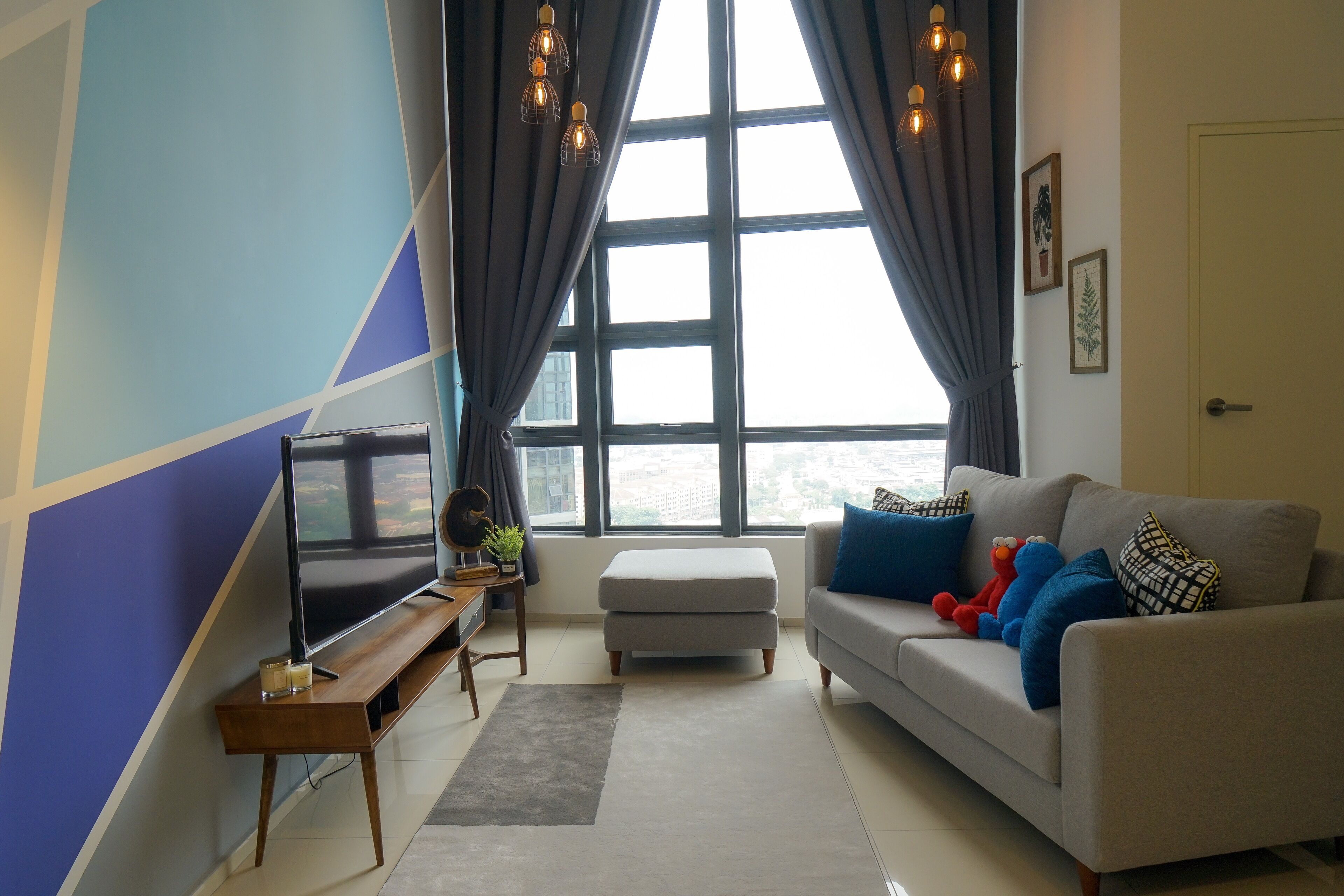 A modern living room with a large window, a sofa, a TV, and a small table with a plant.
