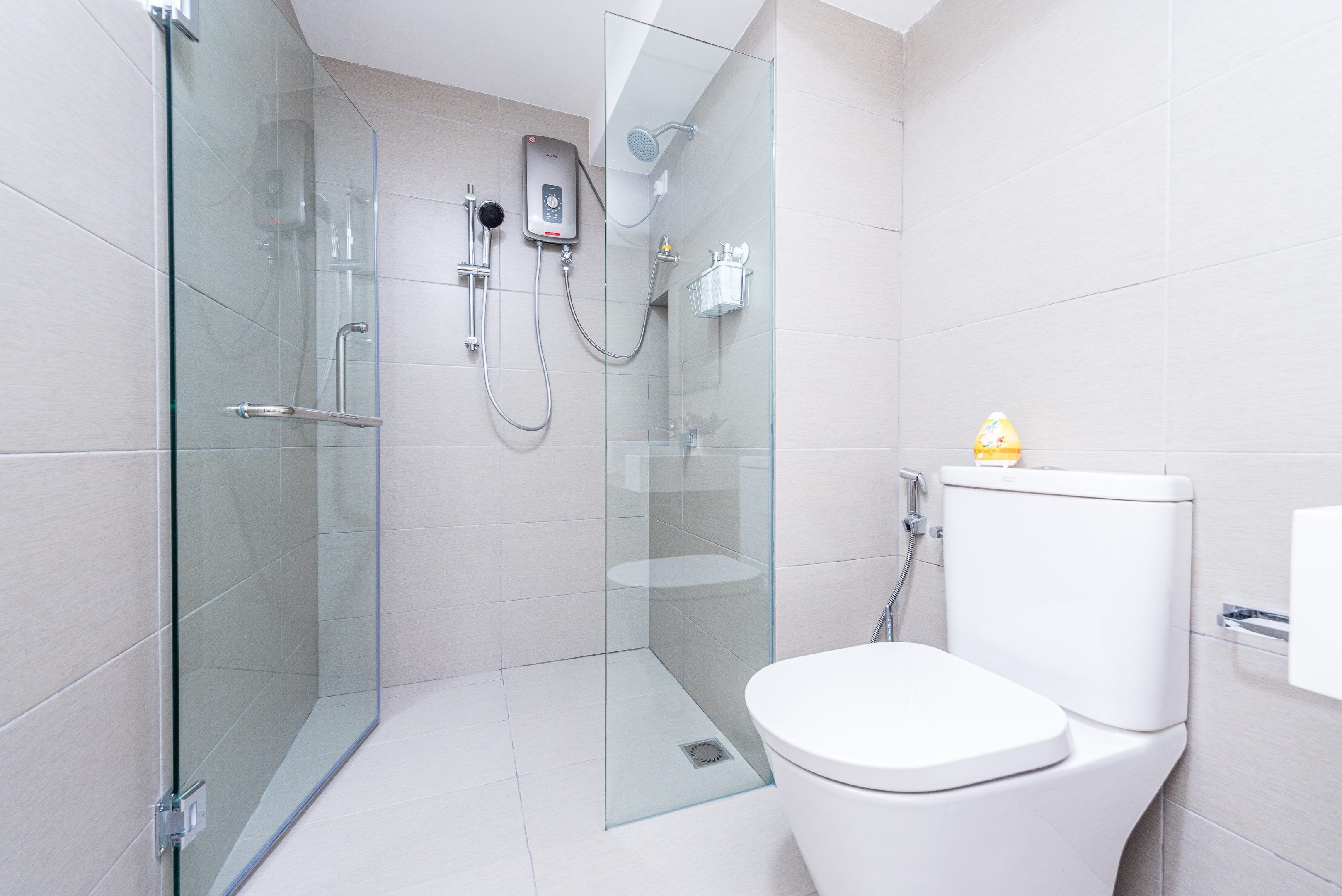 Un bany modern amb dutxa tancada per vidre, un vàter blanc i un lavabo de vidre.
