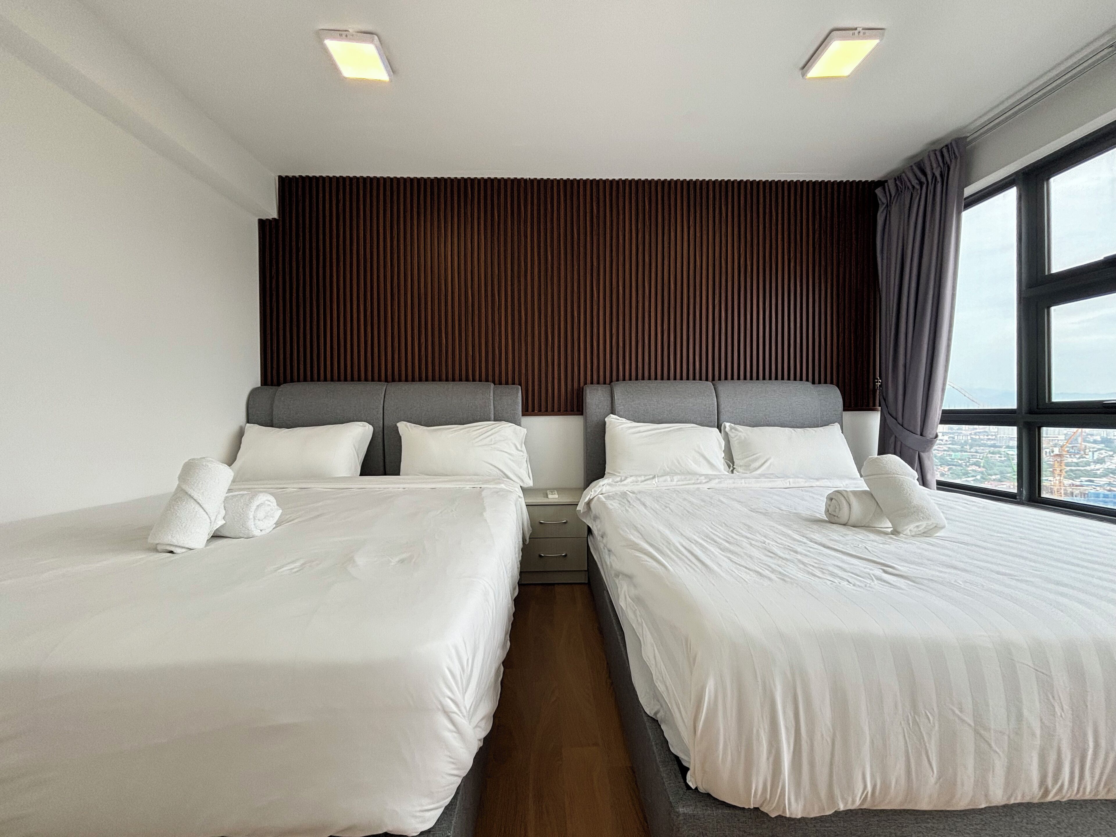 A hotel room with two beds, a wooden headboard, and a large window offering a city view.
