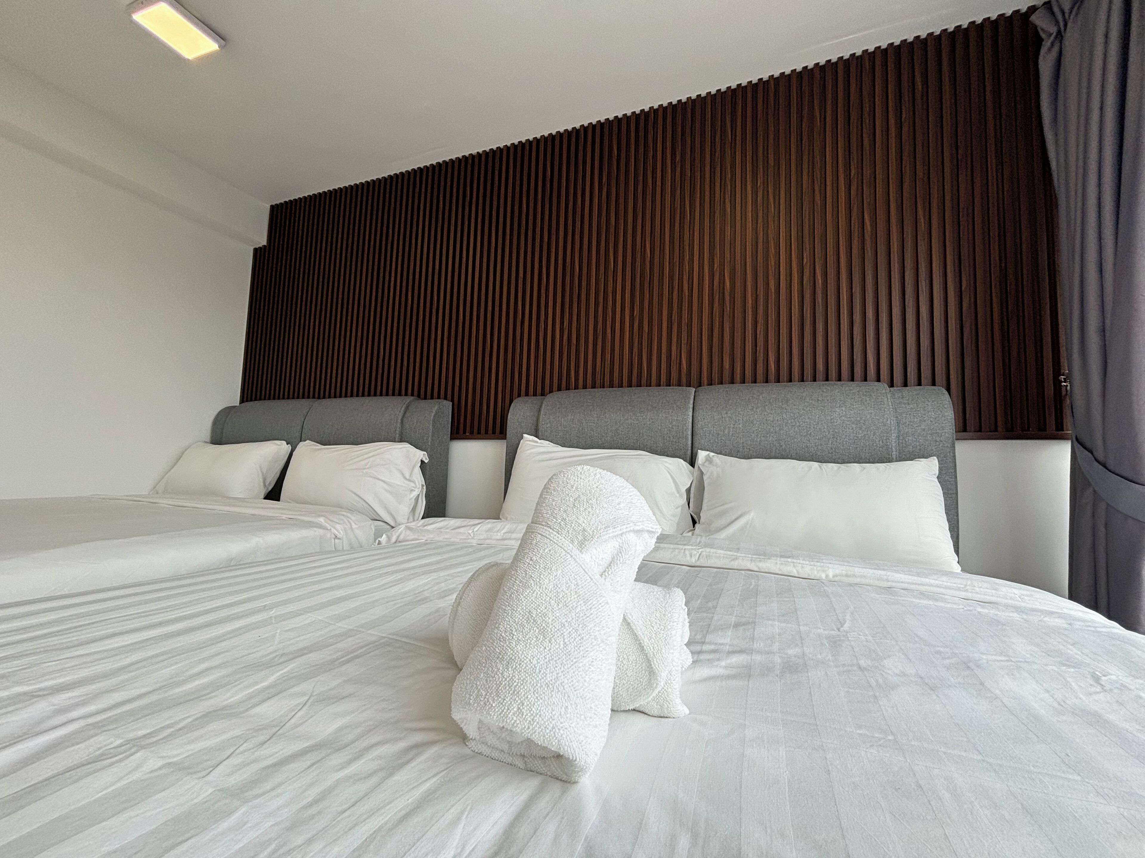 A modern hotel room with two beds, a wooden slatted headboard, and a large window with curtains.