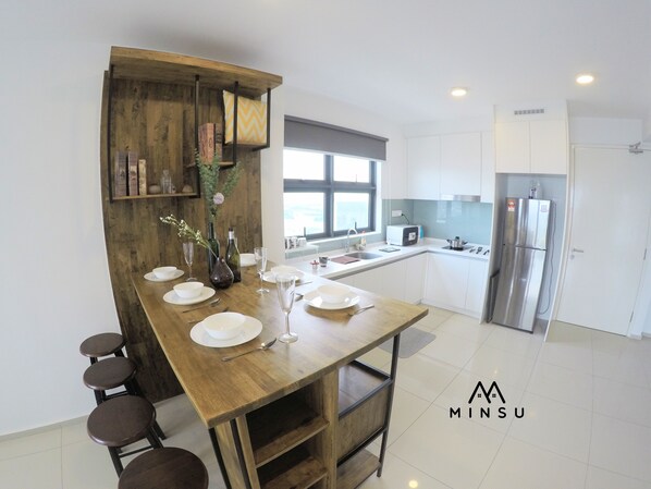 A modern kitchen with a wooden island, white cabinets, and a stainless steel refrigerator.