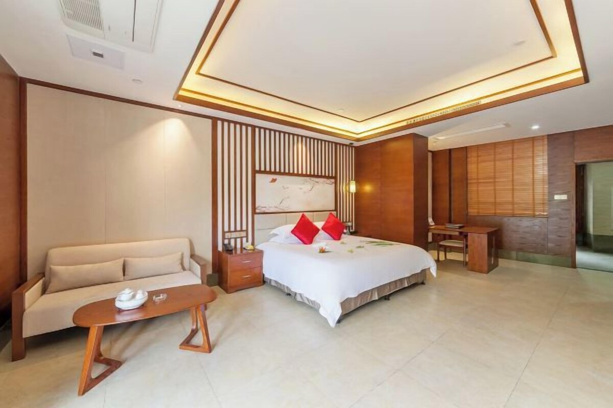 A modern hotel room with a bed, a sofa, a small table, and a desk.