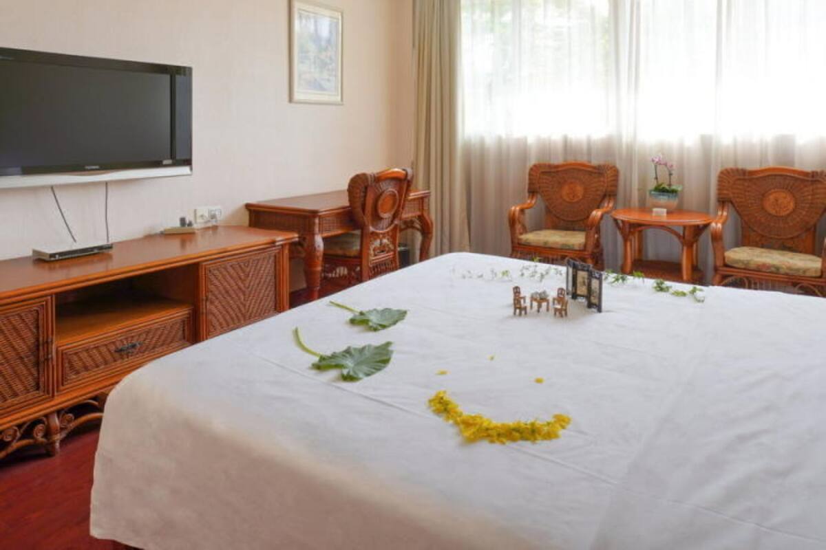 Ett hotellrum med en stor säng, trämöbler, en tv och ett fönster med gardiner.