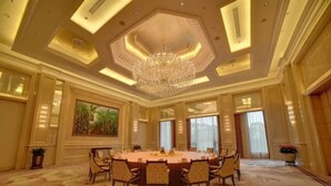 Un'ampia sala conferenze ben illuminata, con un tavolo rotondo, sedie e un lampadario.