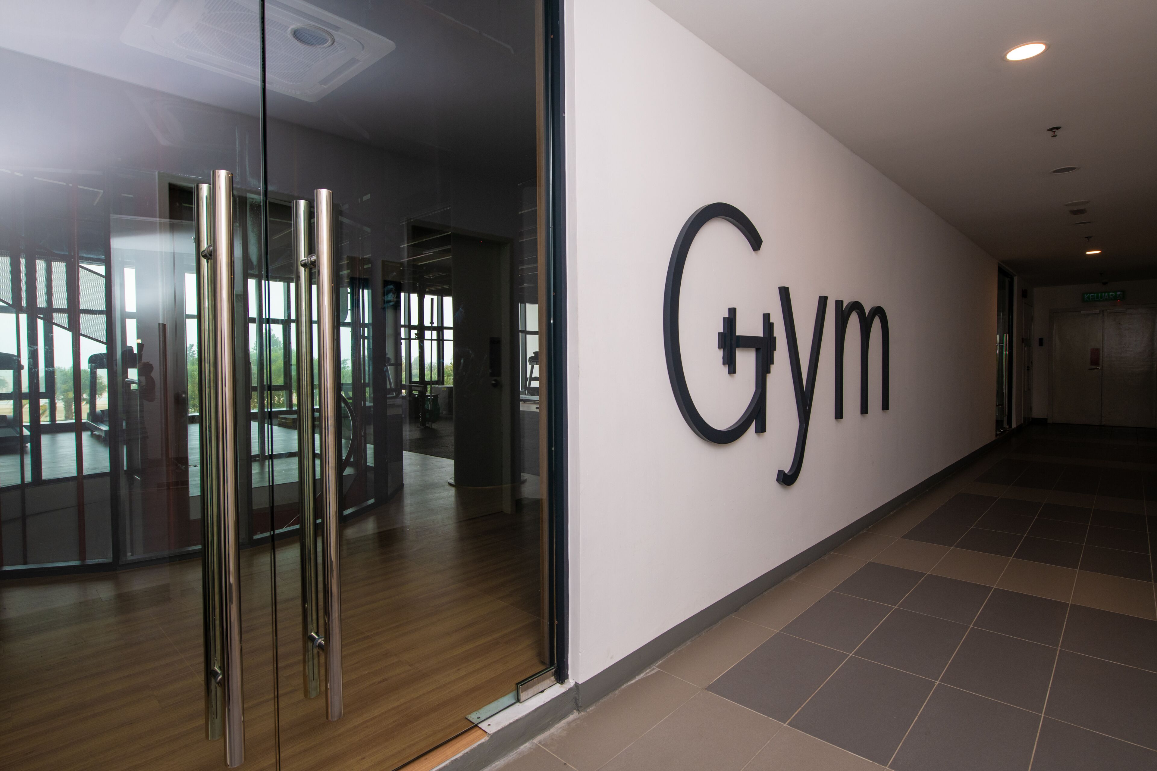 A gym with a large wall sign, glass doors, and a tiled floor.