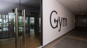 A gym with a large wall sign, glass doors, and a tiled floor.