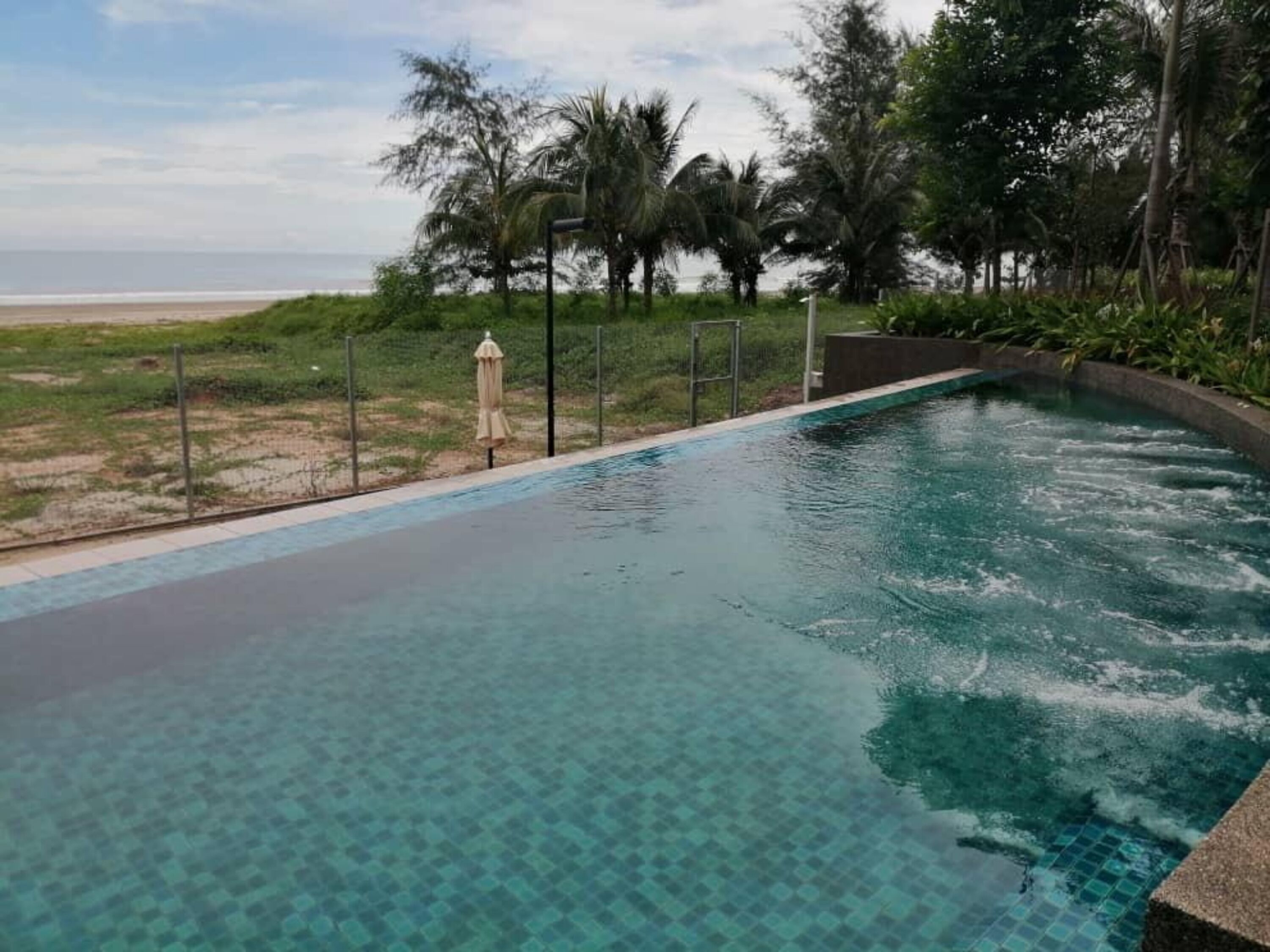 Une piscine à l’eau claire, entourée de verdure et offrant une vue sur la plage.
