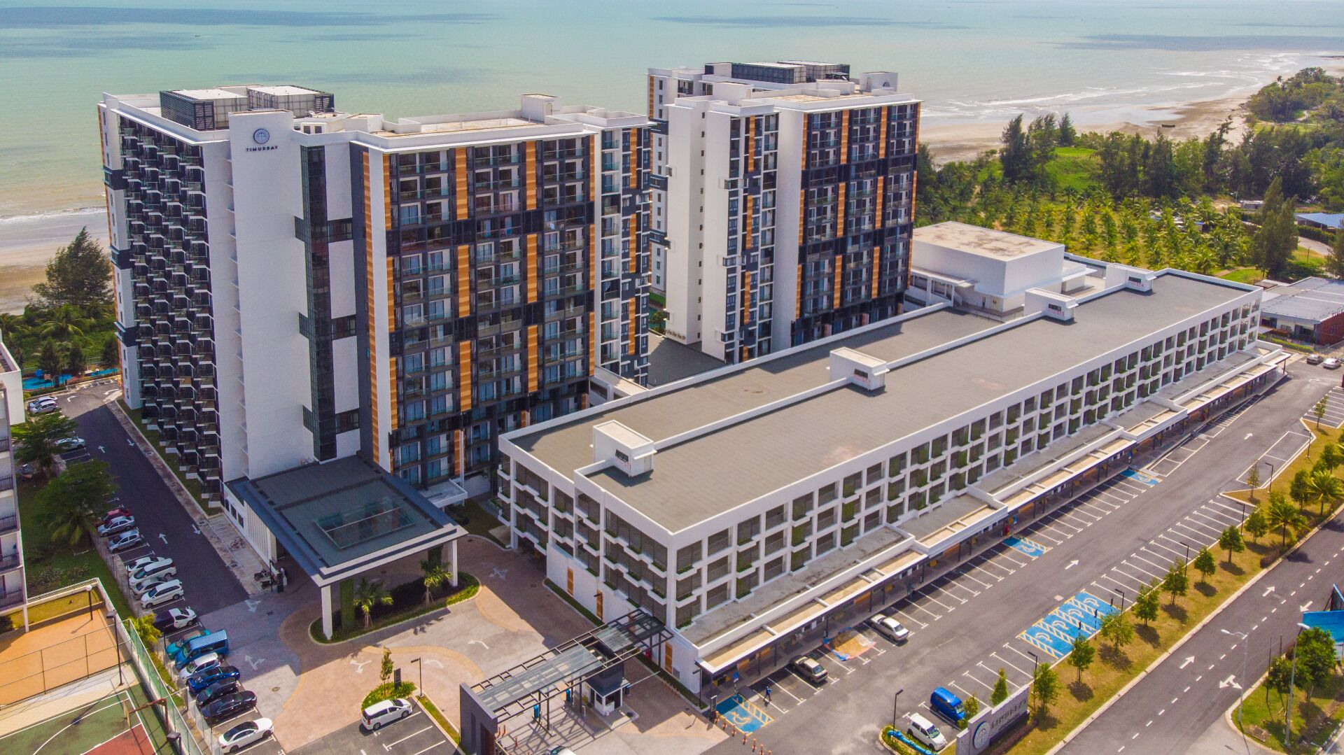 Un hotel moderno con varios edificios altos, un estacionamiento y vistas a la playa.