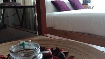A room with a bed, a decorative lantern, and a glass jar with a green lid on a woven mat.
