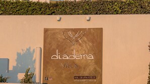 Eingang einer Villa mit einem Schild, das "diadema villa" zeigt, einer Treppe und zwei Kübelpflanzen.