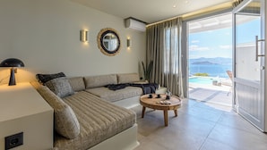 Ein modernes Wohnzimmer mit einer Couch, einem Couchtisch und Blick auf einen Pool und Berge.