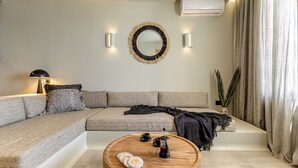 Ein modernes Wohnzimmer mit einem Ecksofa, einem runden Holztisch und einem an der Wand befestigten Spiegel.